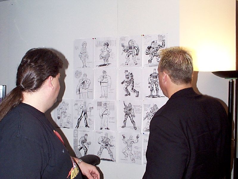 A photo of George Broussard and Andy LaCombe (who portrayed Duke at various E3 shows) looking at a wall of concept art by Dan Panosian. Taken on June 26th 1998. A photo of George Broussard and Andy LaCombe (who portrayed Duke at various E3 shows) looking at a wall of concept art by Dan Panosian. Taken on June 26th 1998.
