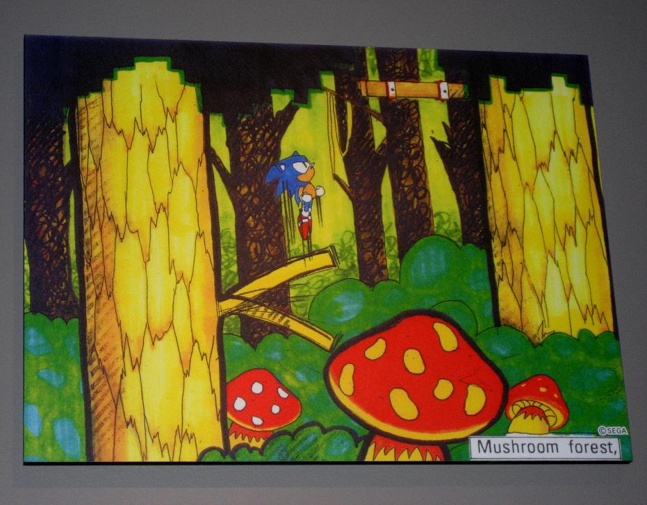 A piece titled "Mushroom Forest", which would become Mushroom Hill. The concept art is modified from a piece of Sonic 2 concept art for "Secret Jungle". Unlike many of the reused Sonic 2 concepts which were simply recolored, this one has also been partially redrawn, increasing the amount of foliage in the lower half to obscure a platform and a hole in the right-hand tree from the original version of the artwork, and also adding the stage's signature giant mushrooms.
